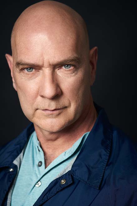 Theatrical headshot of character actor with intense expression and cinematic lighting