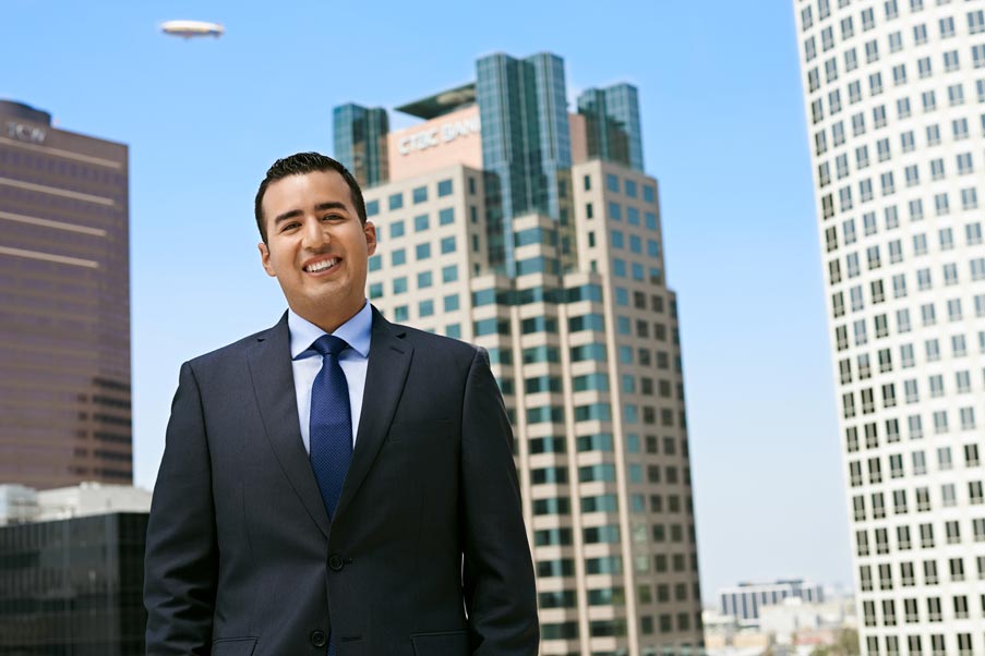 Professional headshot of man in suit with Los Angeles office buildings in background
